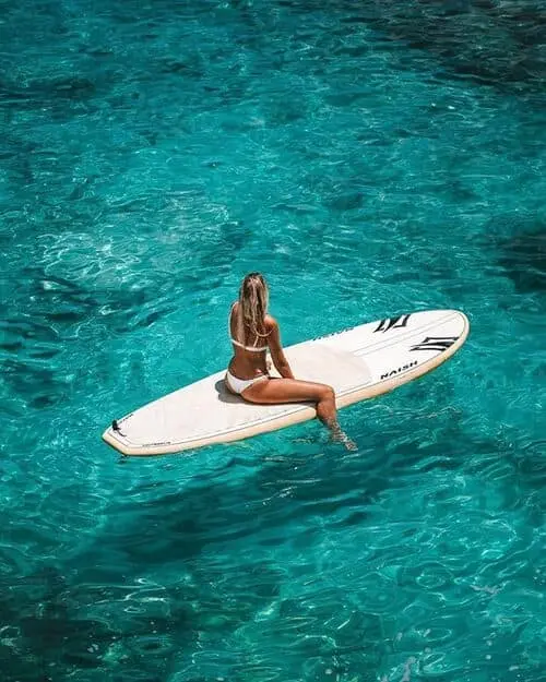 a woman sitting on a surfboard in the sea