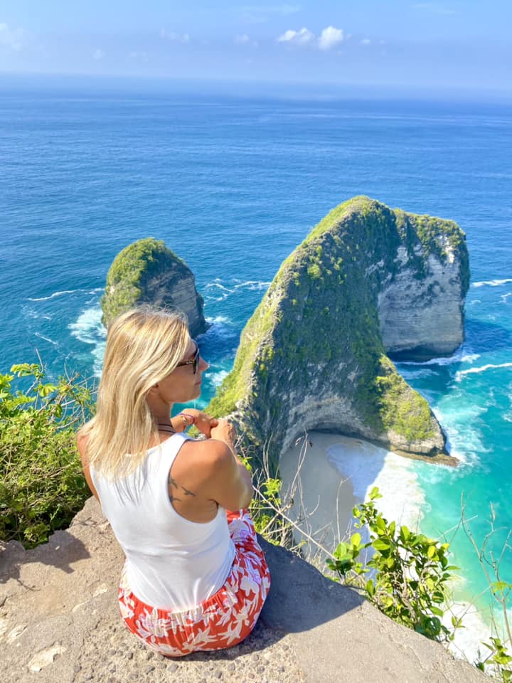 a woman sitting on a rock and looking at the sea