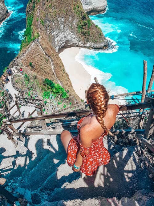 a woman going down the stairs and looking at the sea